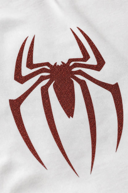Close view of the red glitter spider print on white cotton