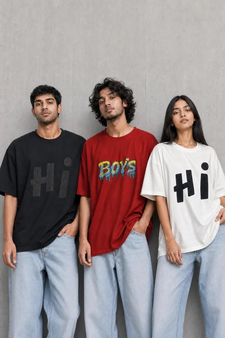 Three people wearing Jalapeno oversized tees against a concrete wall